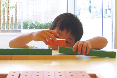 かずの木で電車あそび:かずの木ピンを挿すとき、子どもは慎重に真剣になります